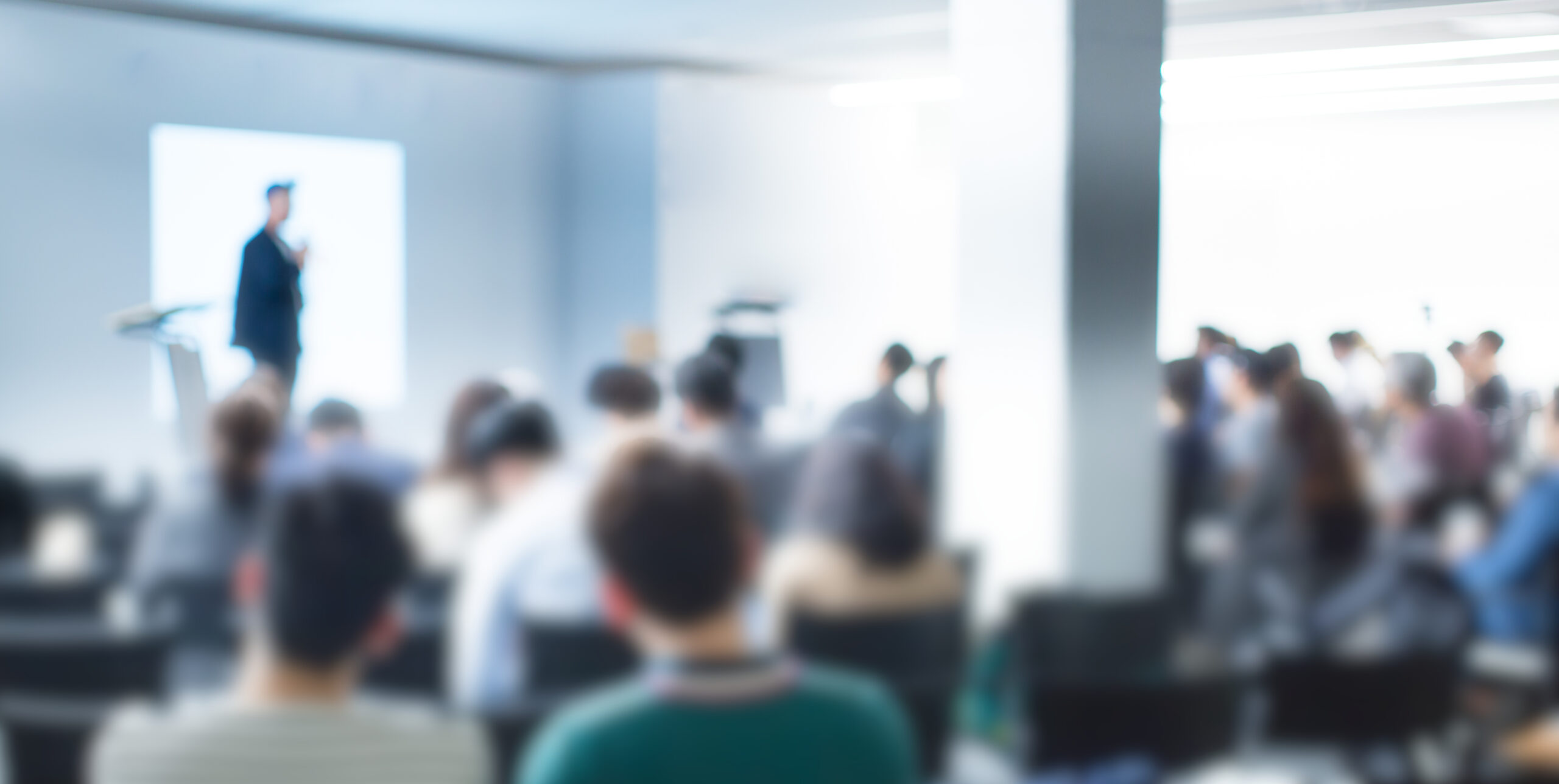 Blurred De-focused Audience in Conference Lecture Presentation Room. Corporate Presentations in Conference Hall.